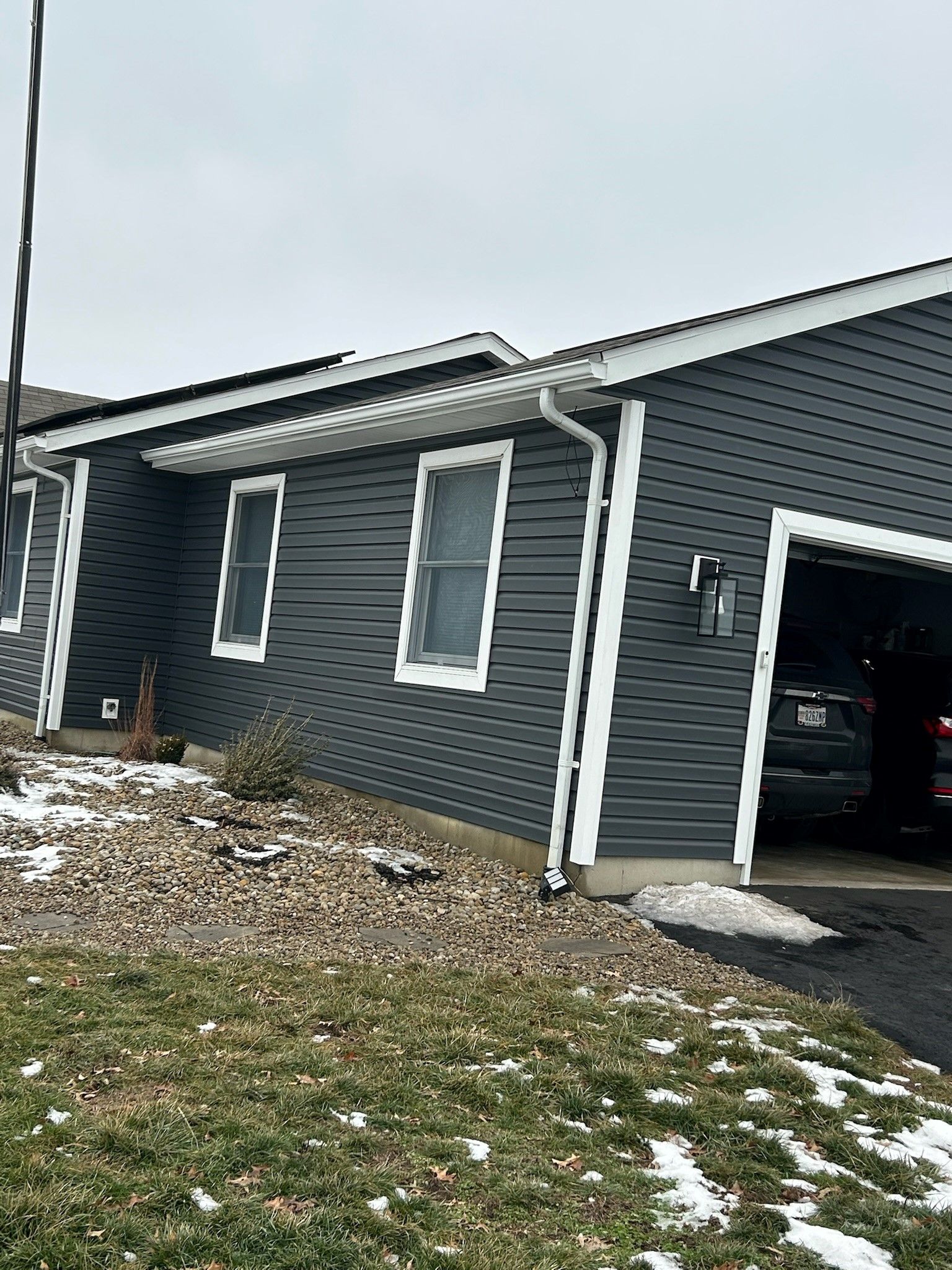 A house with a garage and a basketball hoop in front of it.