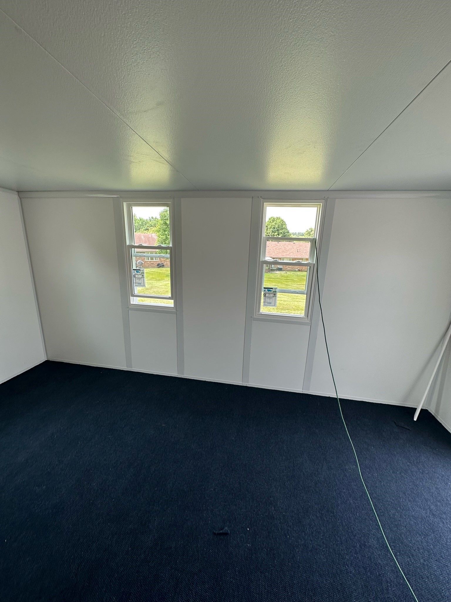 An empty room with a blue carpet and three windows.