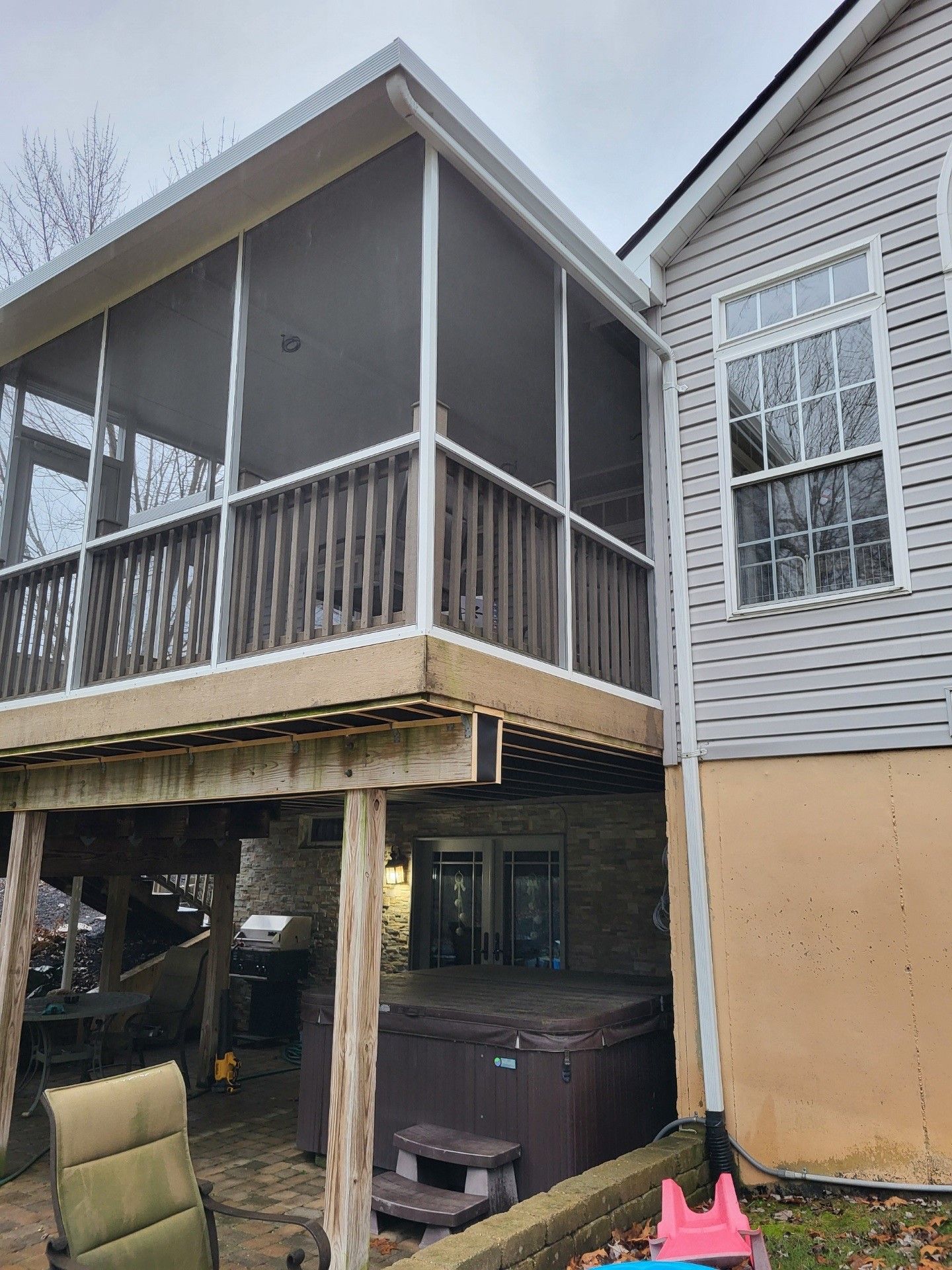 A house with a screened in porch and a hot tub underneath it.