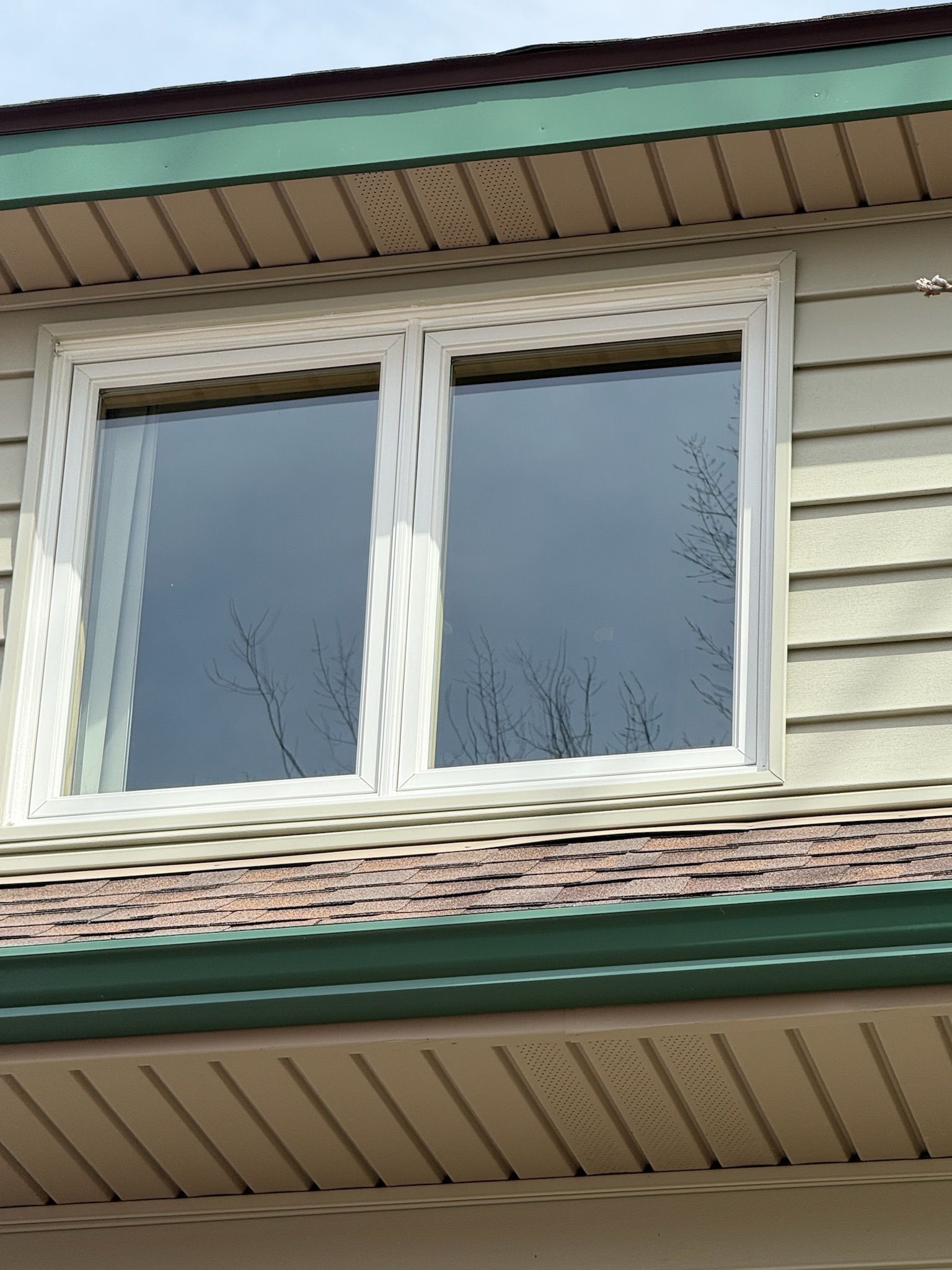 A house with two windows and a green roof.