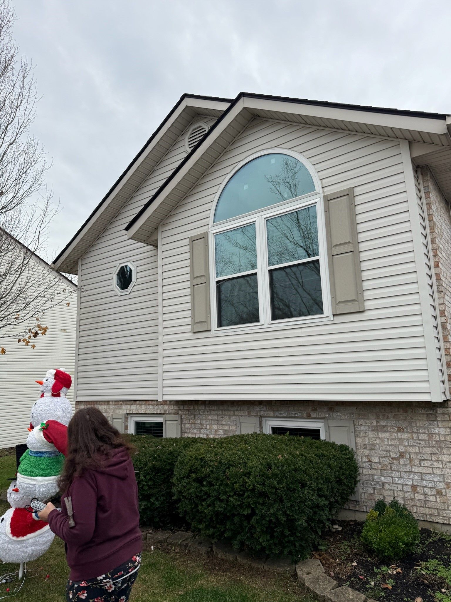 A woman is standing in front of a house decorated for christmas.