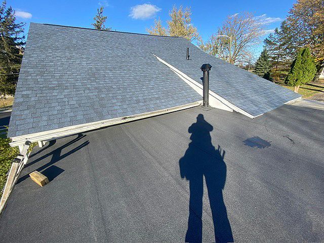 A shadow of a person is cast on the roof of a house.