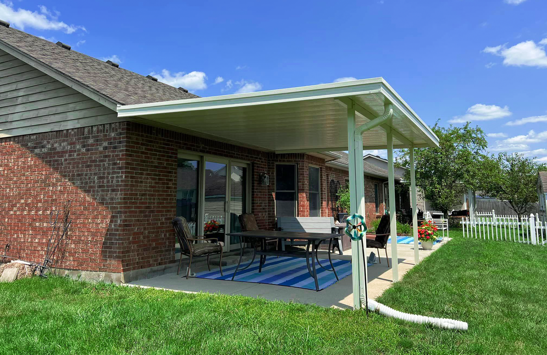 There is a patio with a table and chairs under a covered patio cover.