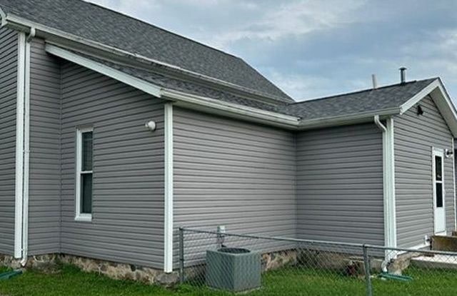 The side of a house with a gray siding and a gray roof.