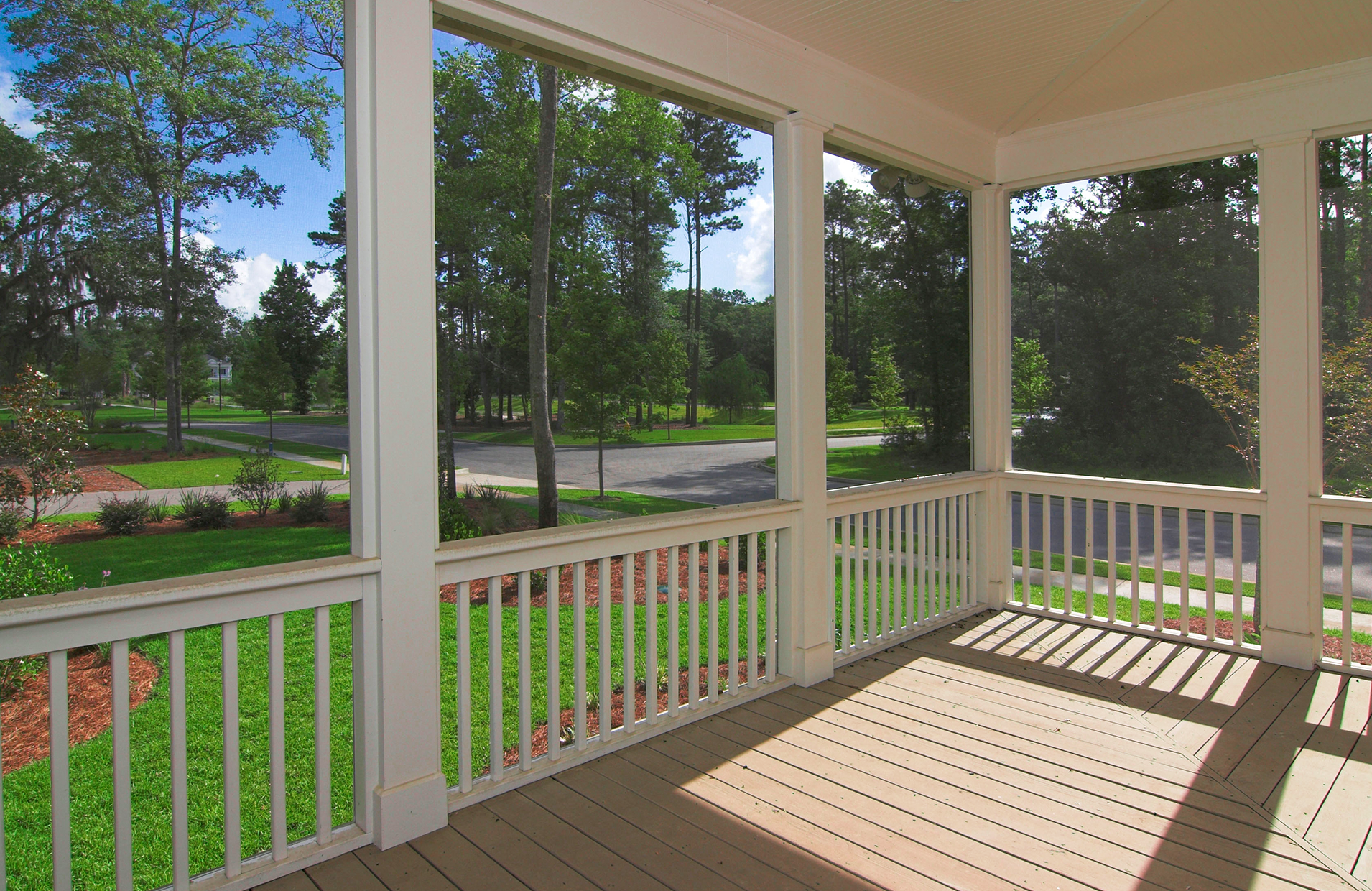 An empty screened-in porch with trees in the background