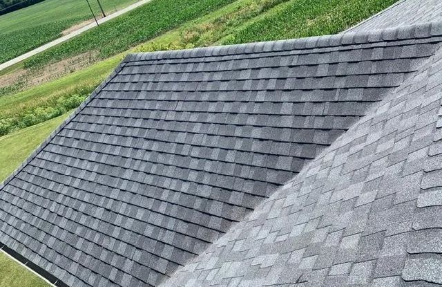 The roof of a house with a lot of shingles and a field in the background.