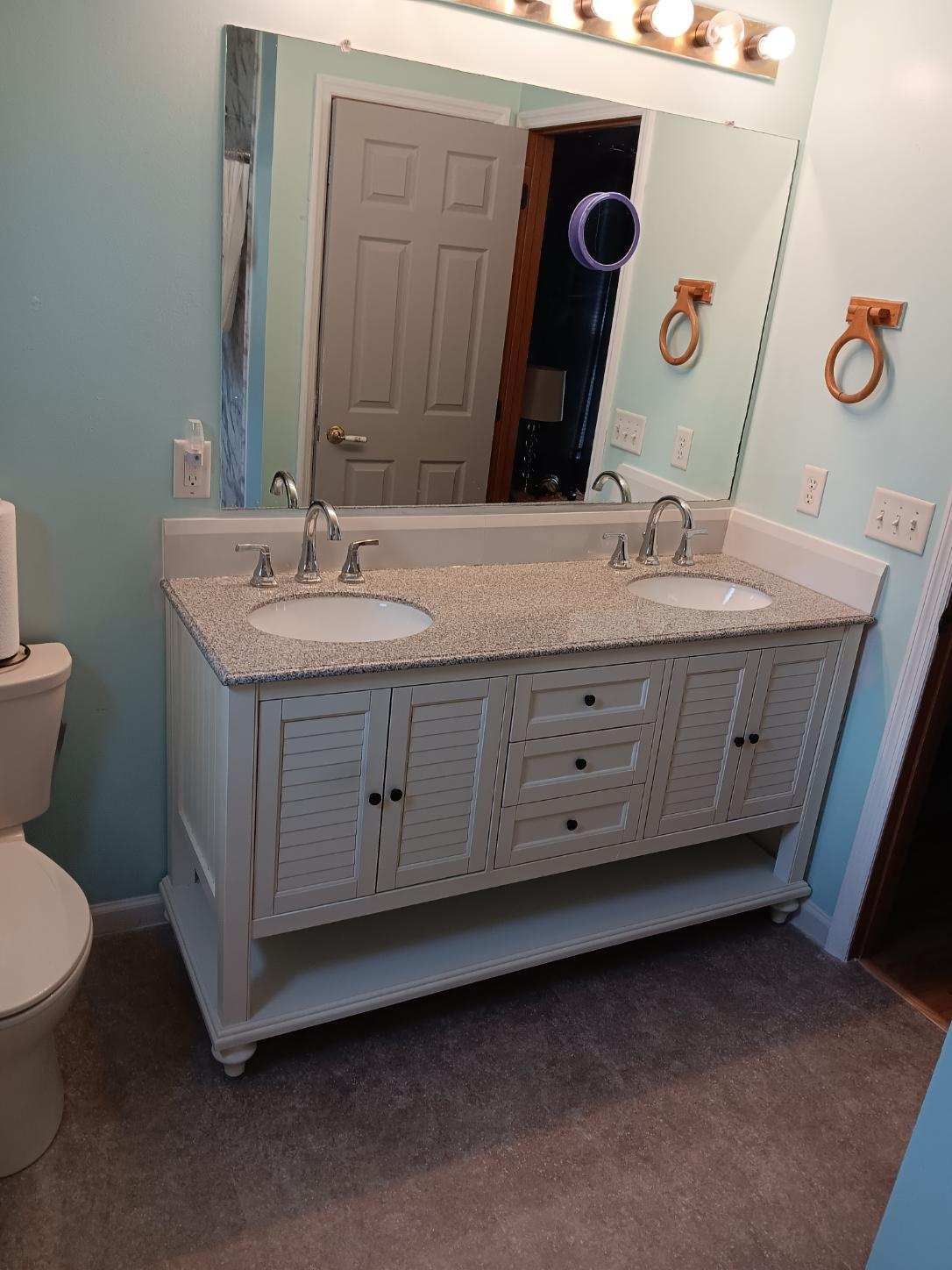A bathroom with two sinks , a toilet and a mirror.