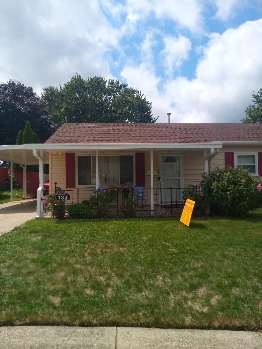 A house with a red roof and a yellow sign in front of it