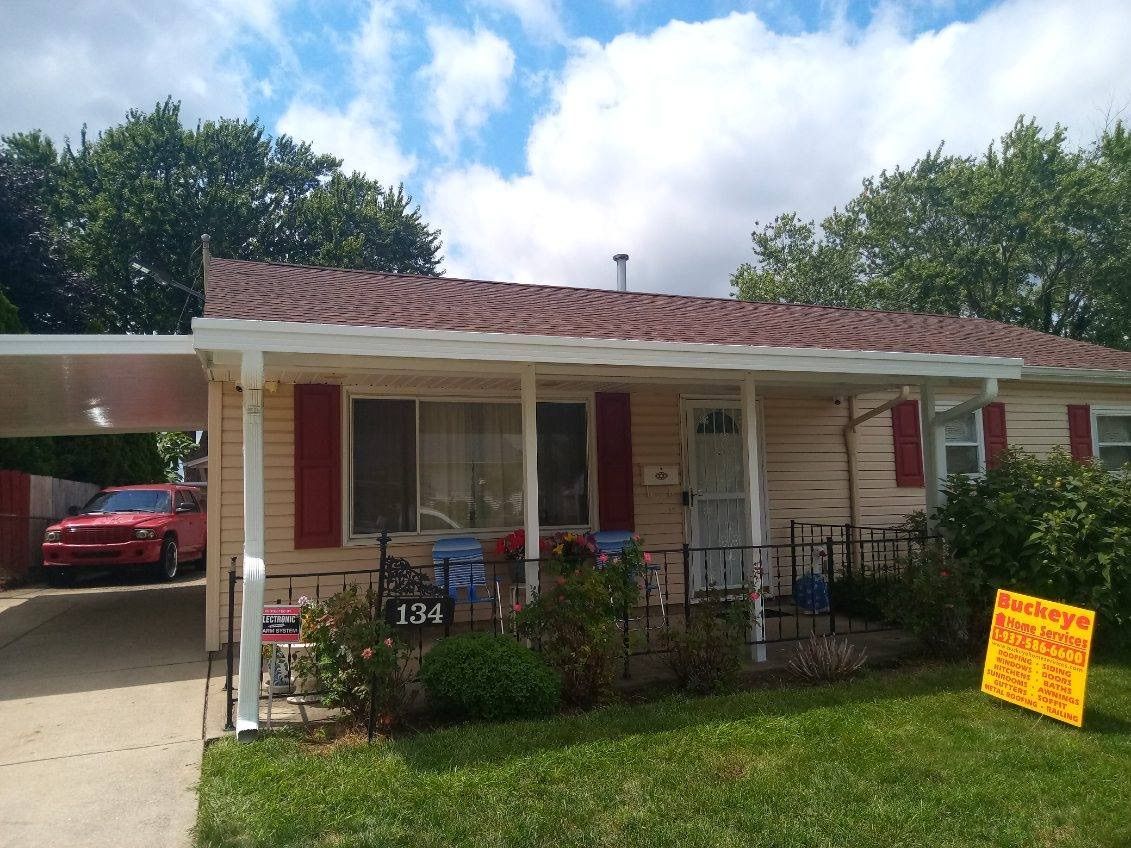 A house with a car parked in front of it and a for sale sign in front of it.