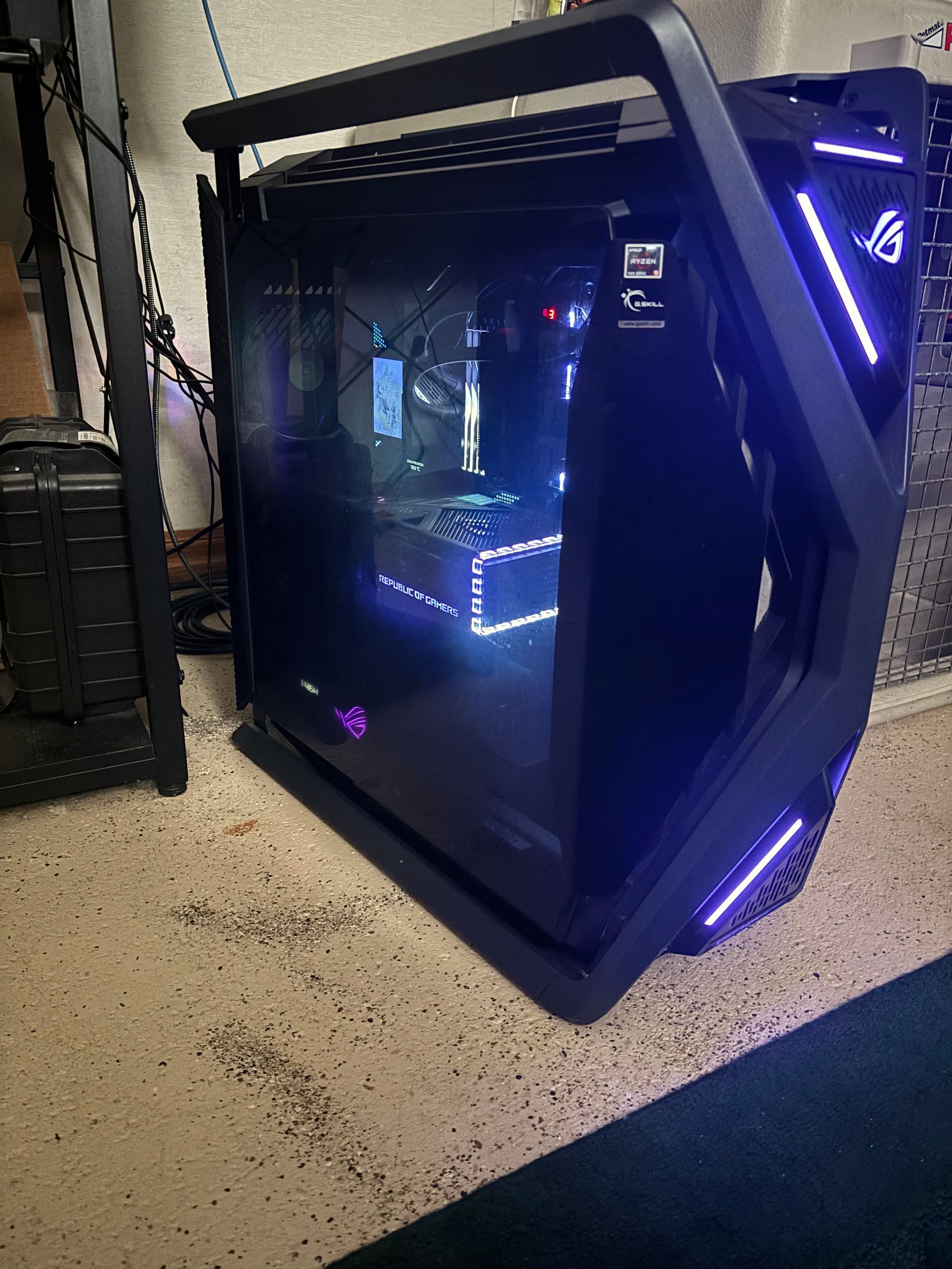 A lit-up black gaming PC with blue lights and a glass side panel in a room on a concrete floor.