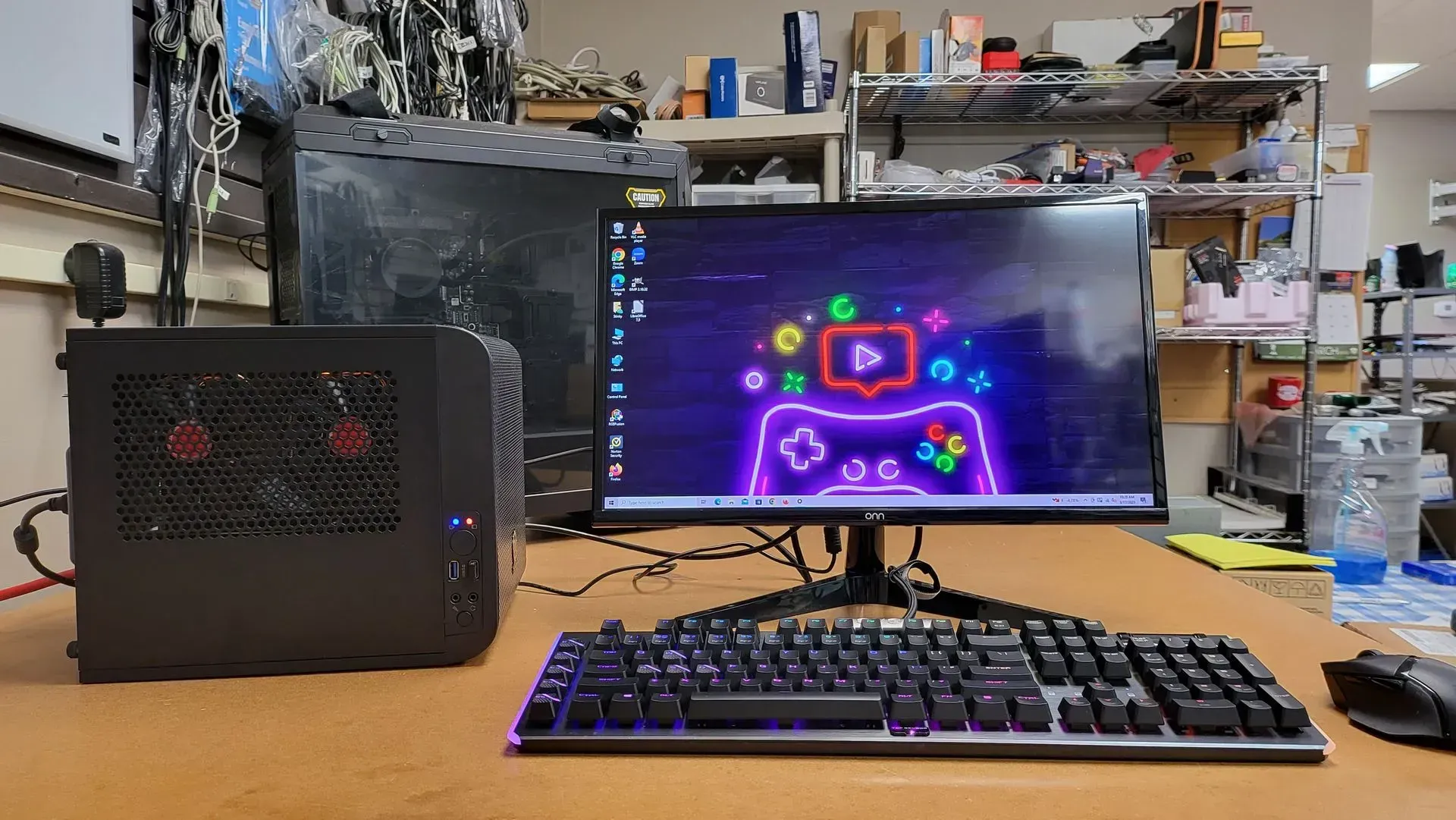 Black PC setup on a desk, featuring a monitor with a colorful gaming-themed wallpaper, keyboard, and mouse.