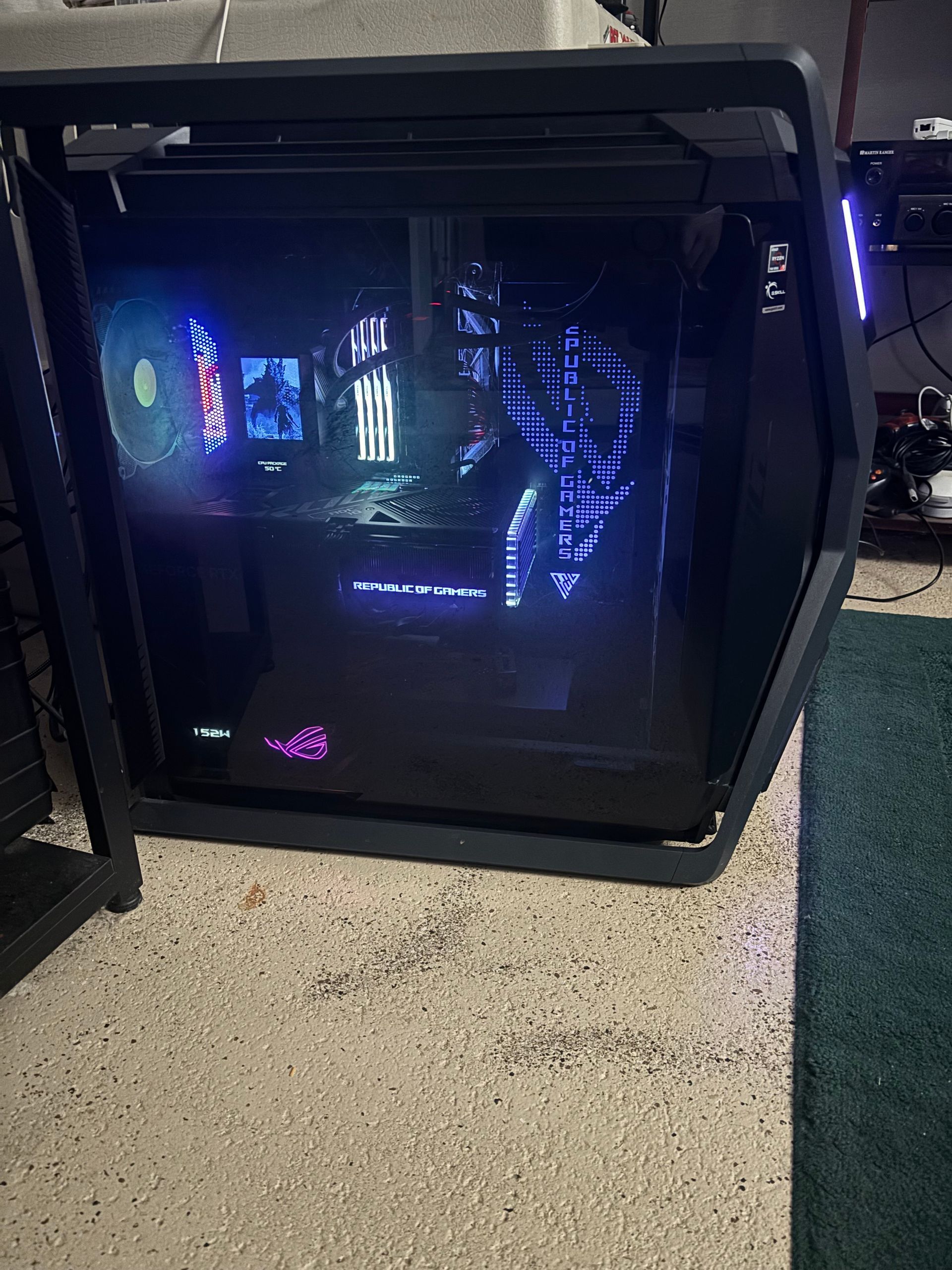 A black gaming PC with blue and purple interior lighting on a concrete floor.