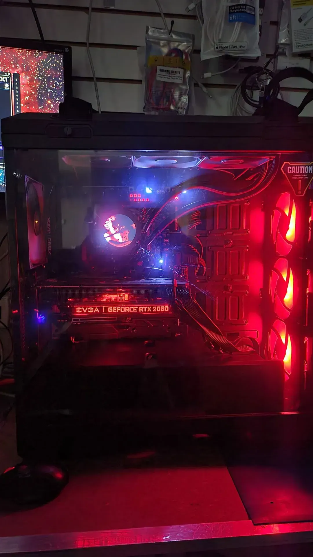 Lit-up gaming PC with red and blue lights, visible components, in a shop setting.