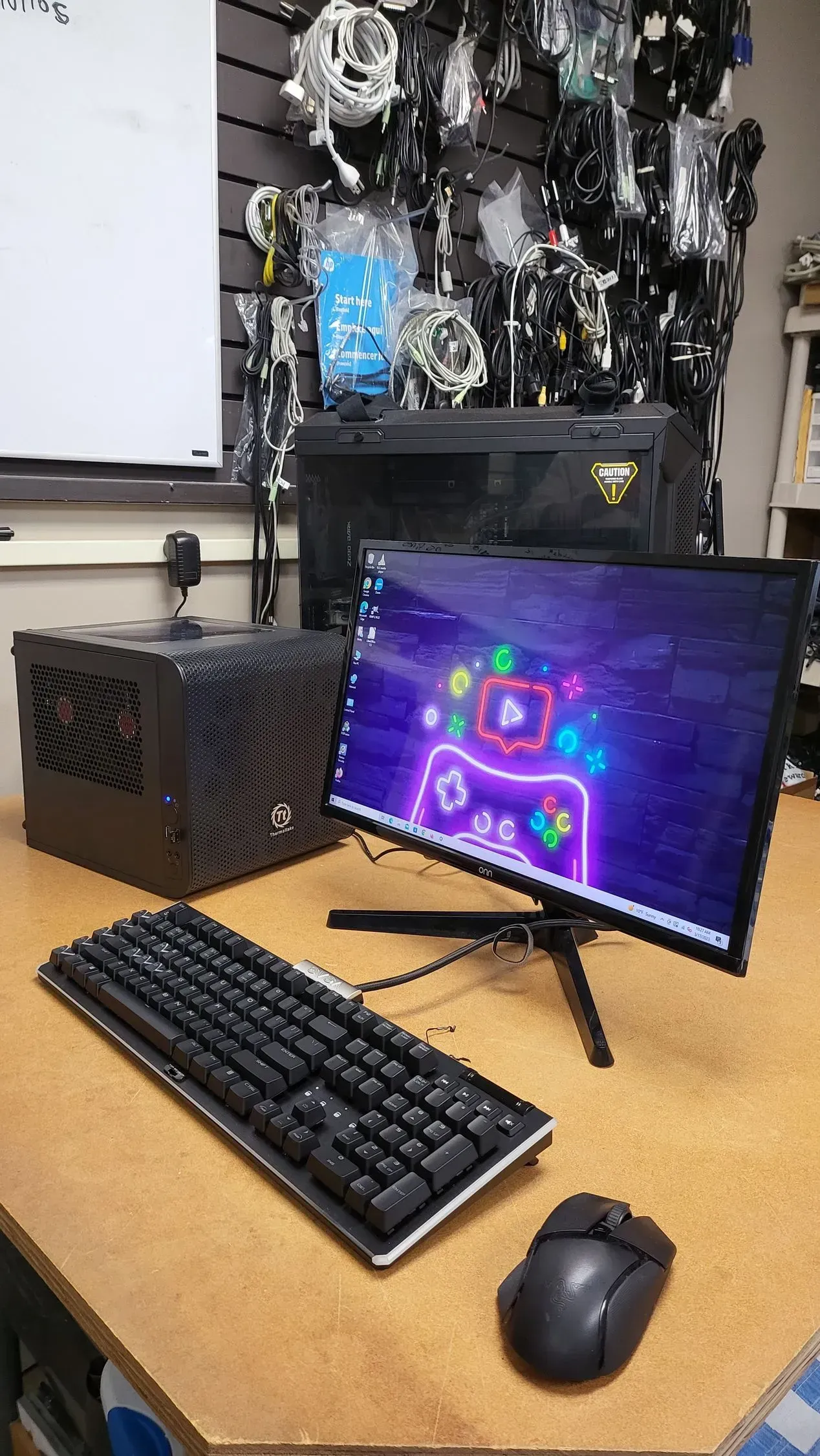 Black computer setup on a desk, featuring a monitor, keyboard, mouse, and a cube-shaped PC case.