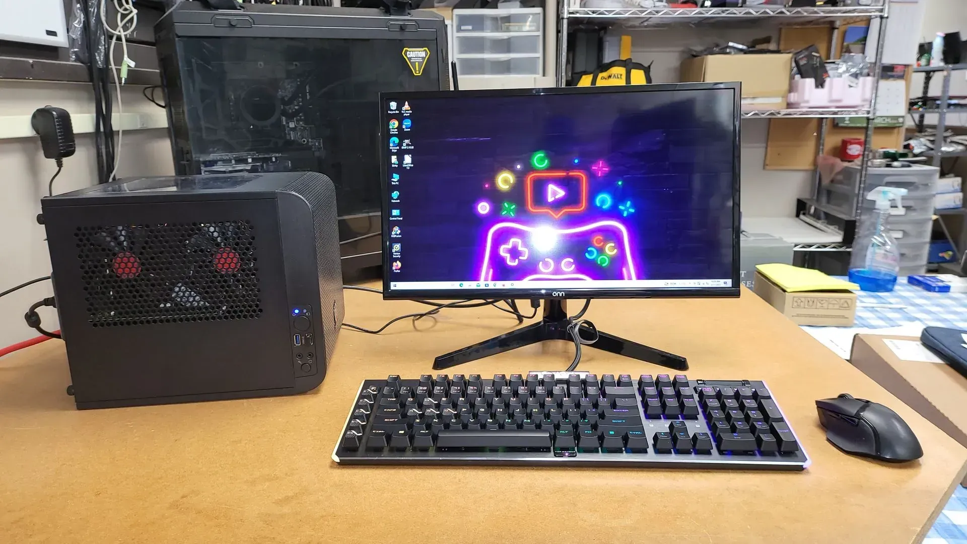 A desktop computer setup with a black PC case, monitor displaying a colorful graphic, keyboard, and mouse on a wooden desk.