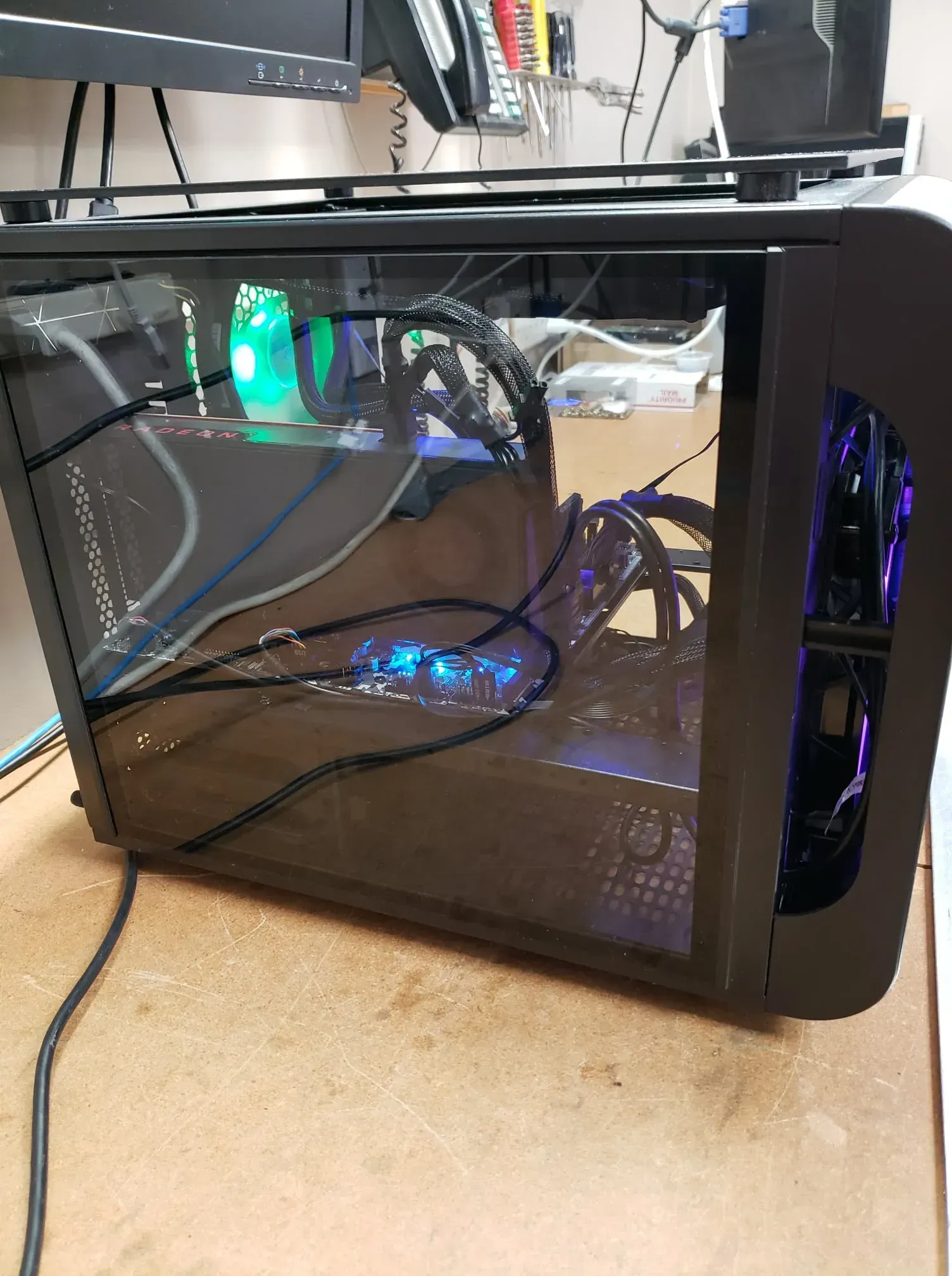 Black computer tower with side window, internal components visible, lit by blue and green lights.