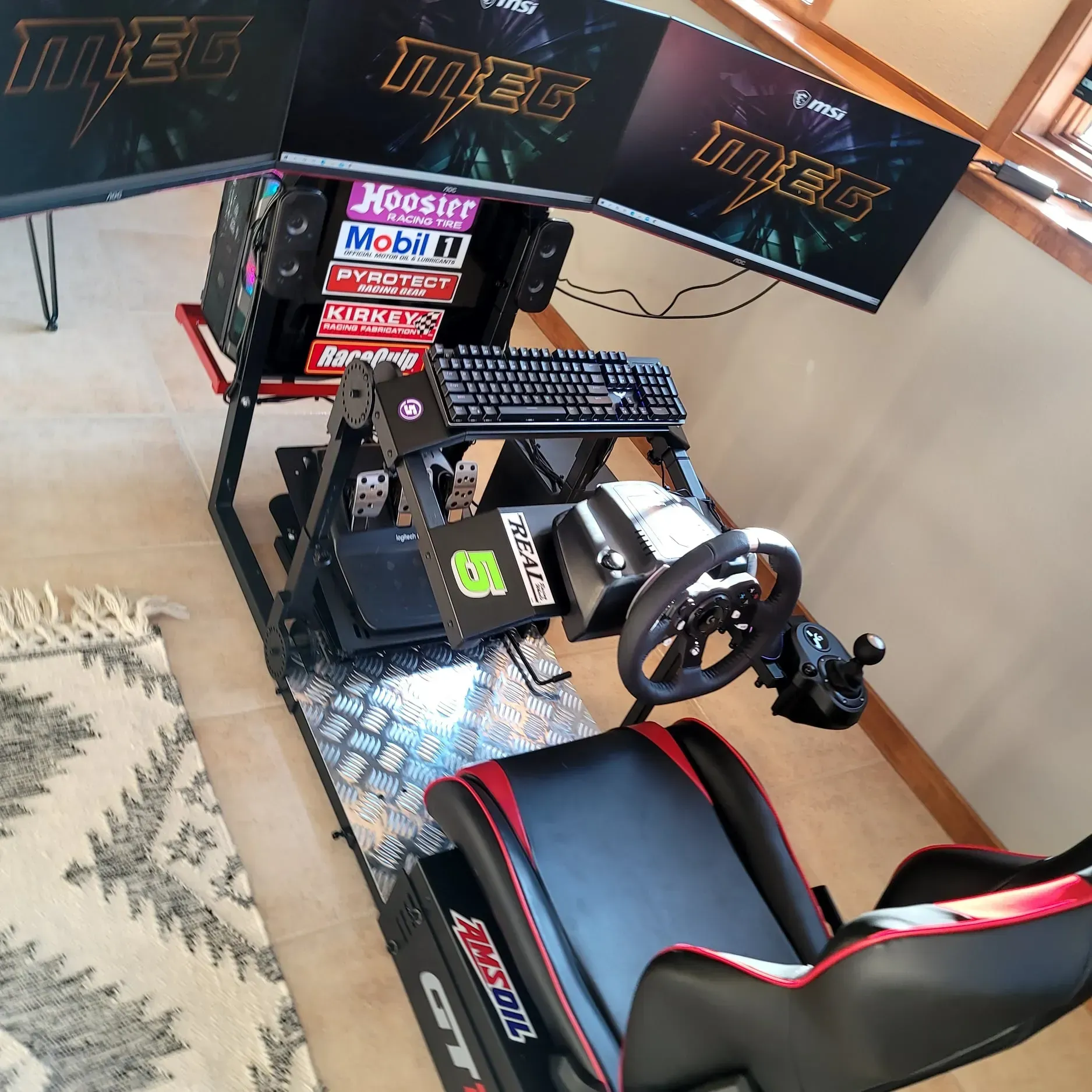 Racing simulator with triple monitors, racing seat, steering wheel, pedals, and keyboard.
