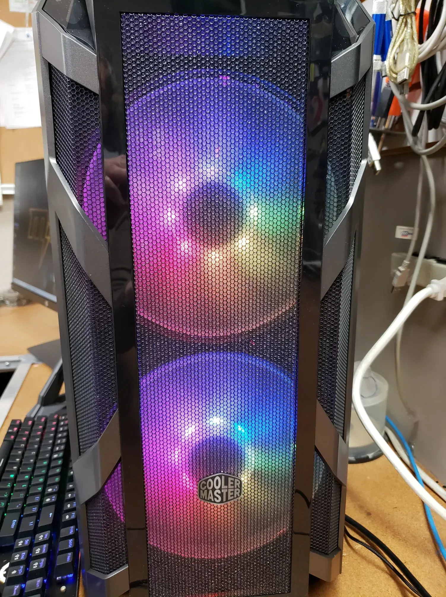 Computer tower with illuminated, multi-colored fans behind a mesh front panel.