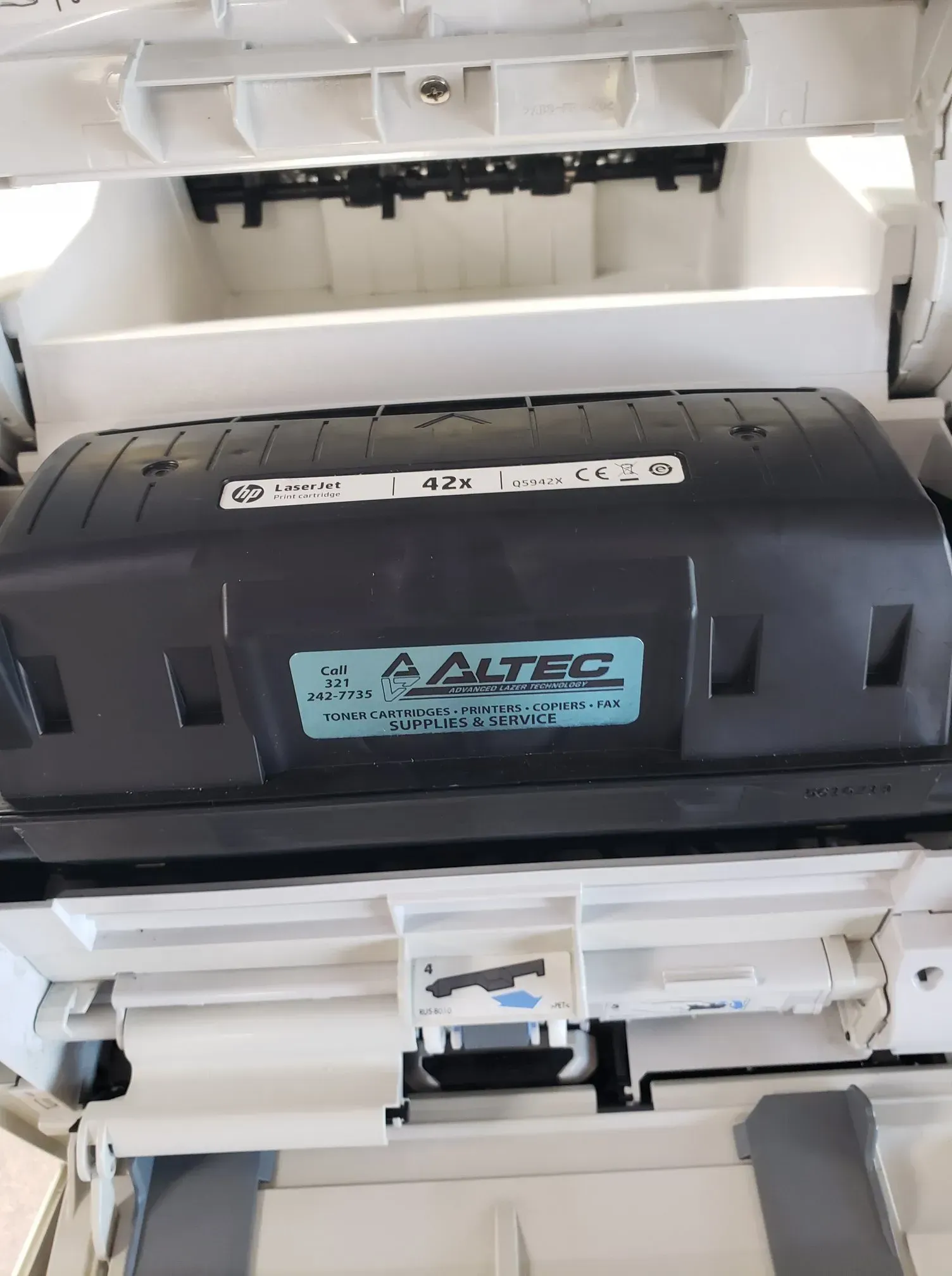 Printer's internal component with a black cartridge labeled 