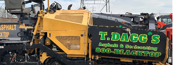 A yellow LeeBoy asphalt paver spreading material on a residential driveway in front of a house.