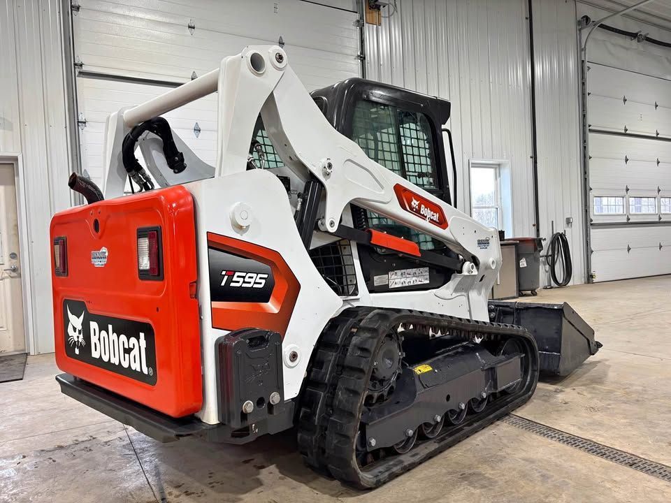 White and orange Bobcat T595 compact track loader in a garage.