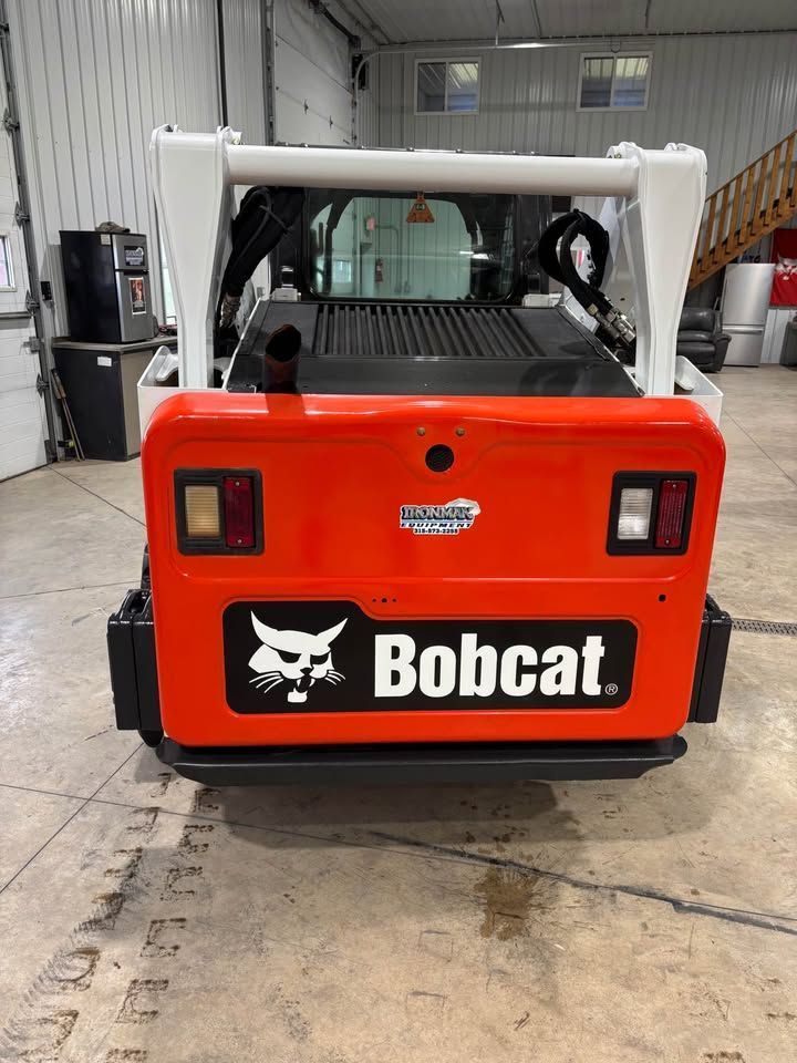 Rear view of an orange and white Bobcat skid-steer loader in a garage.
