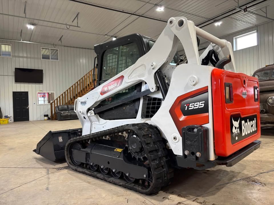 White and orange Bobcat T595 compact track loader on display indoors.