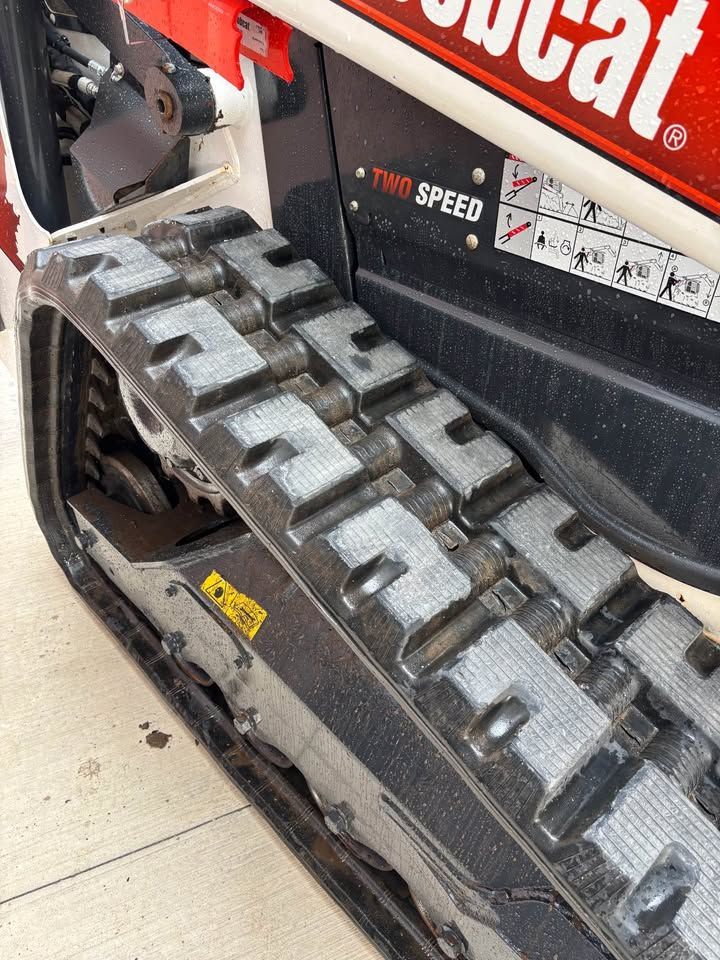 Close-up of a Bobcat compact track loader tread, showing black rubber tracks and the machine's side panel.