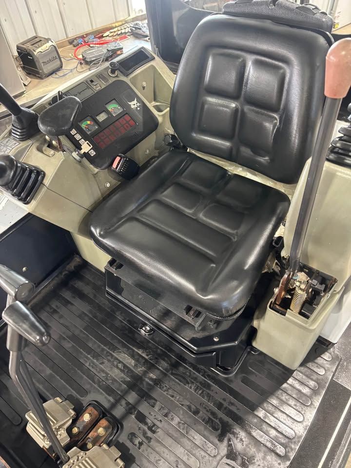Interior of Bobcat construction vehicle, showing operator's seat, control panel, and levers.