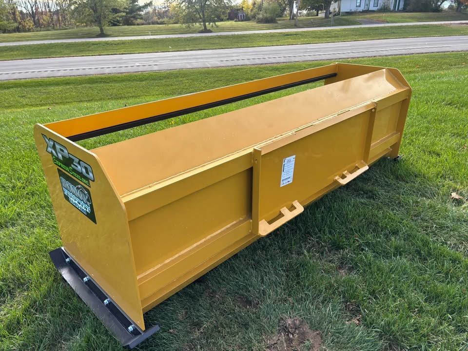 Yellow snow pusher on grass, with black blade, likely for tractor use.