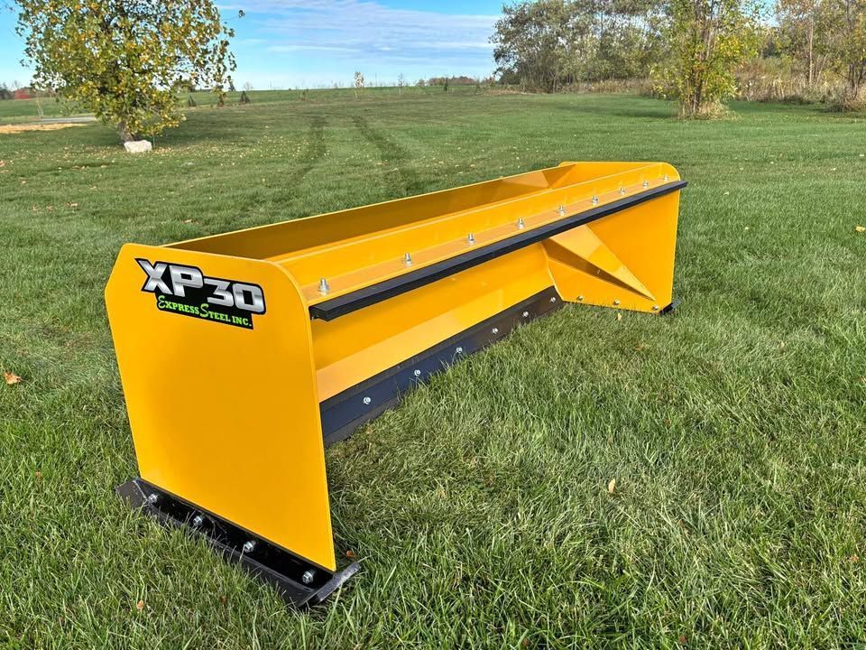 Yellow XP30 snow plow on a grassy lawn with a blue sky in the background.