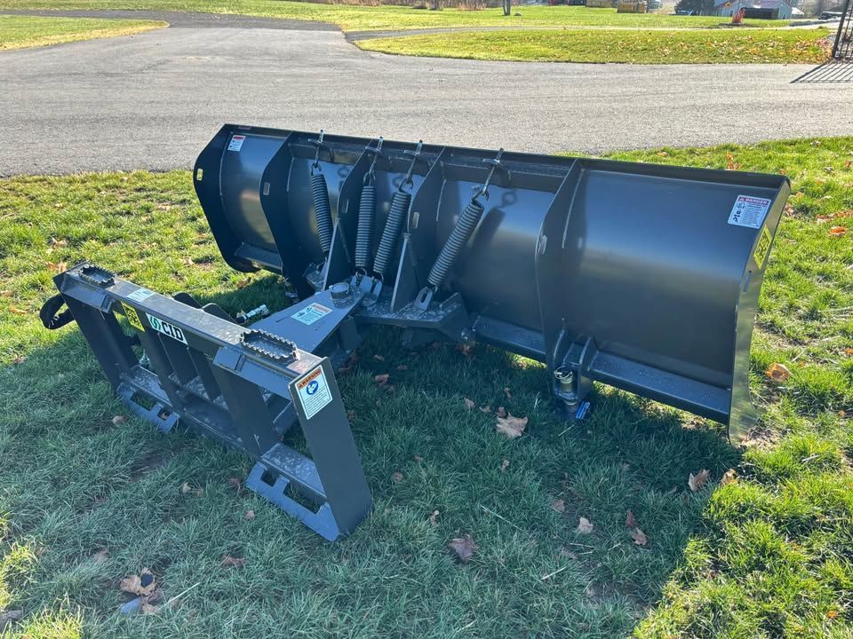 Black snowplow on green grass.
