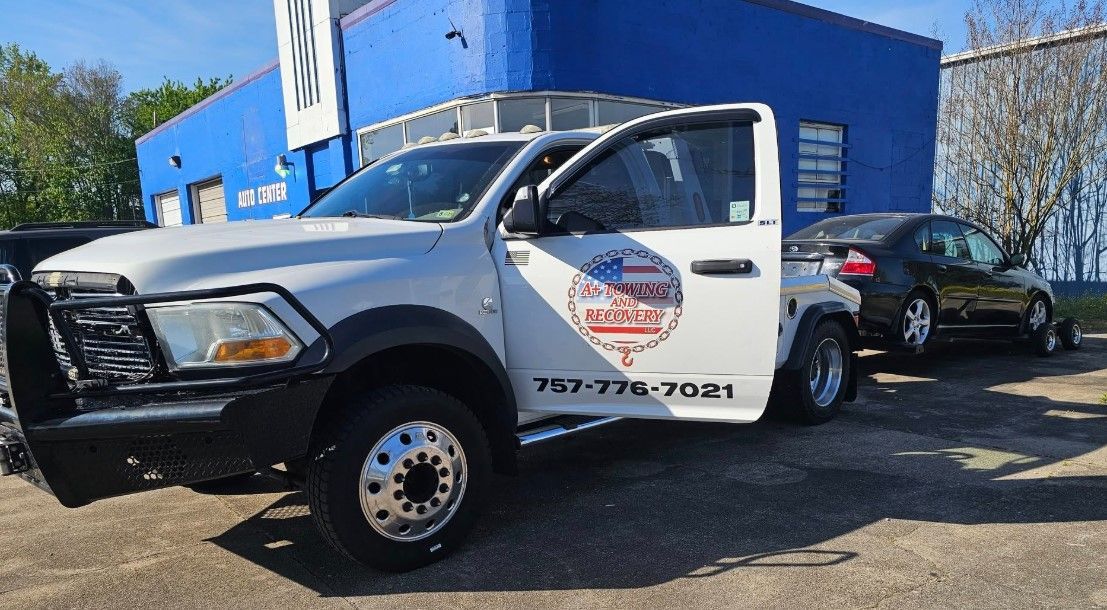 A white truck is parked in front of a blue building.