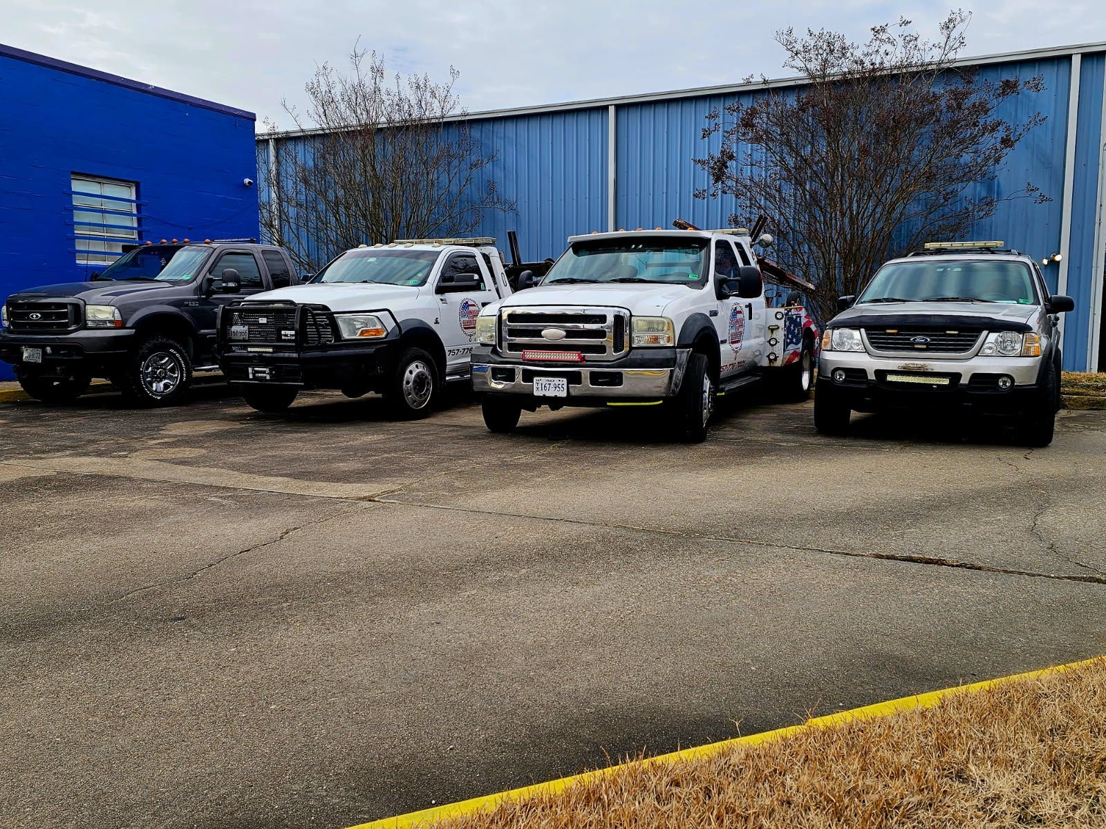 Four parked pickup trucks in front of a blue warehouse