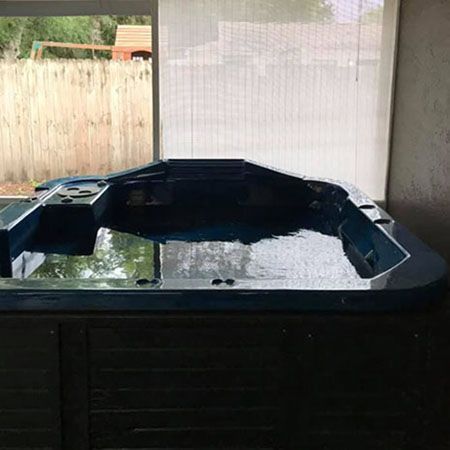 A hot tub is sitting on top of a wooden deck next to a body of water.