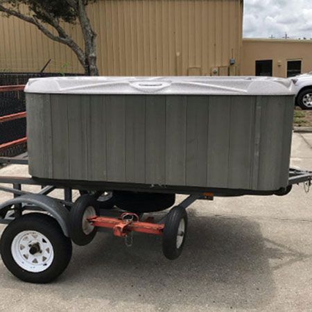 A hot tub is sitting on a brick patio next to a window.