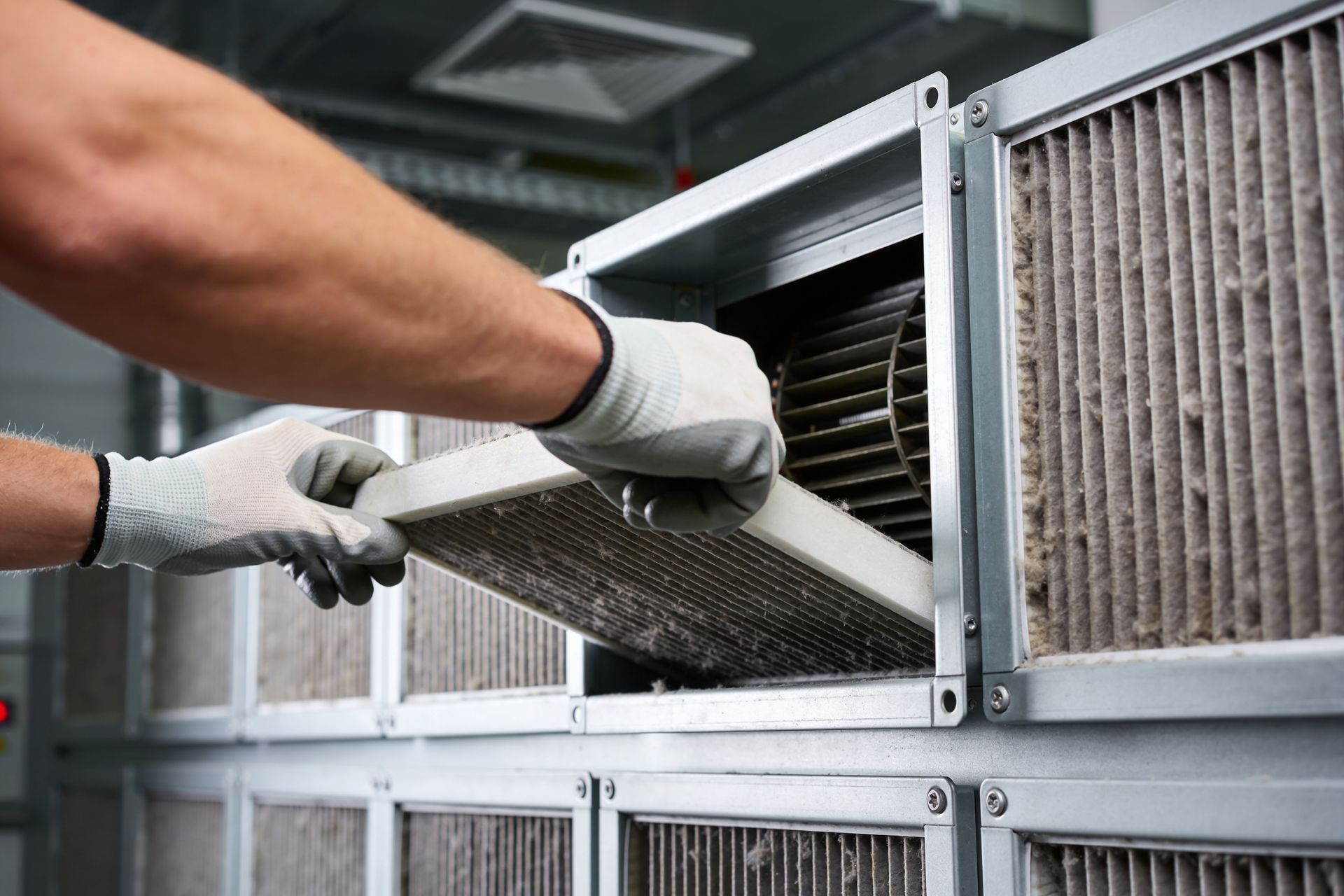 Gloved hands removing an air filter from a ventilation unit