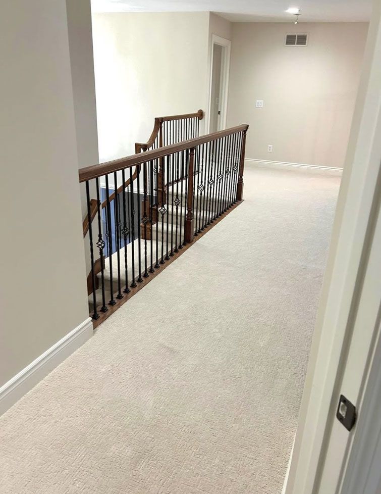 Carpeted upstairs hallway with dark wood railing and beige walls