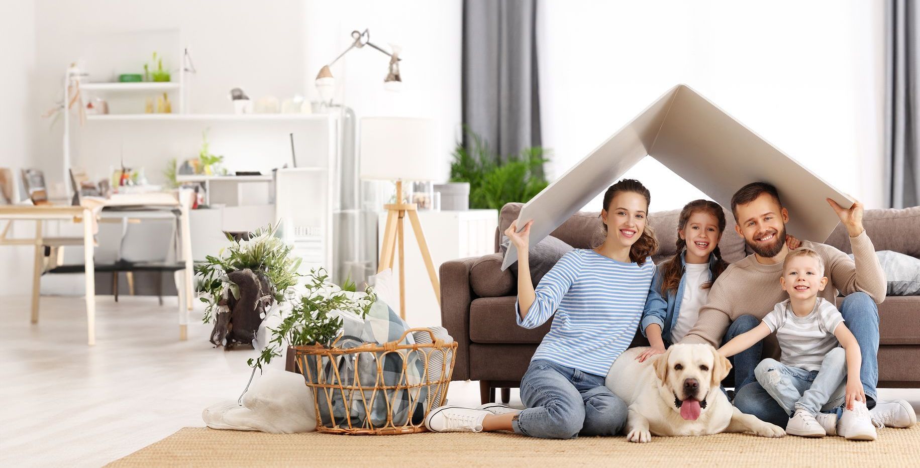 Family under cardboard shelter with dog in cozy living room.