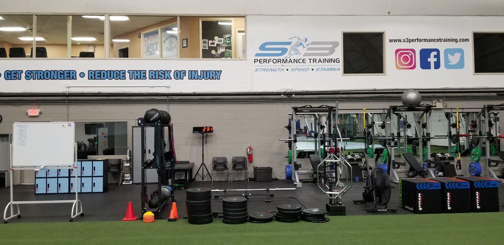 Gym interior with exercise equipment, weights, and wall banners beneath a long banner and social media icons