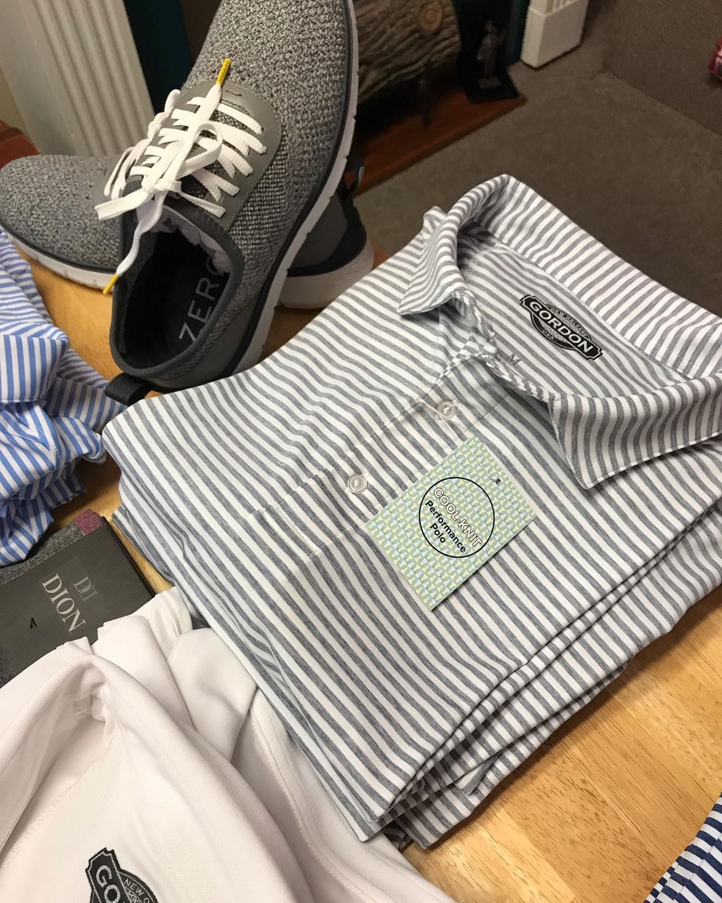 A pair of shoes and a striped shirt are on a wooden table.
