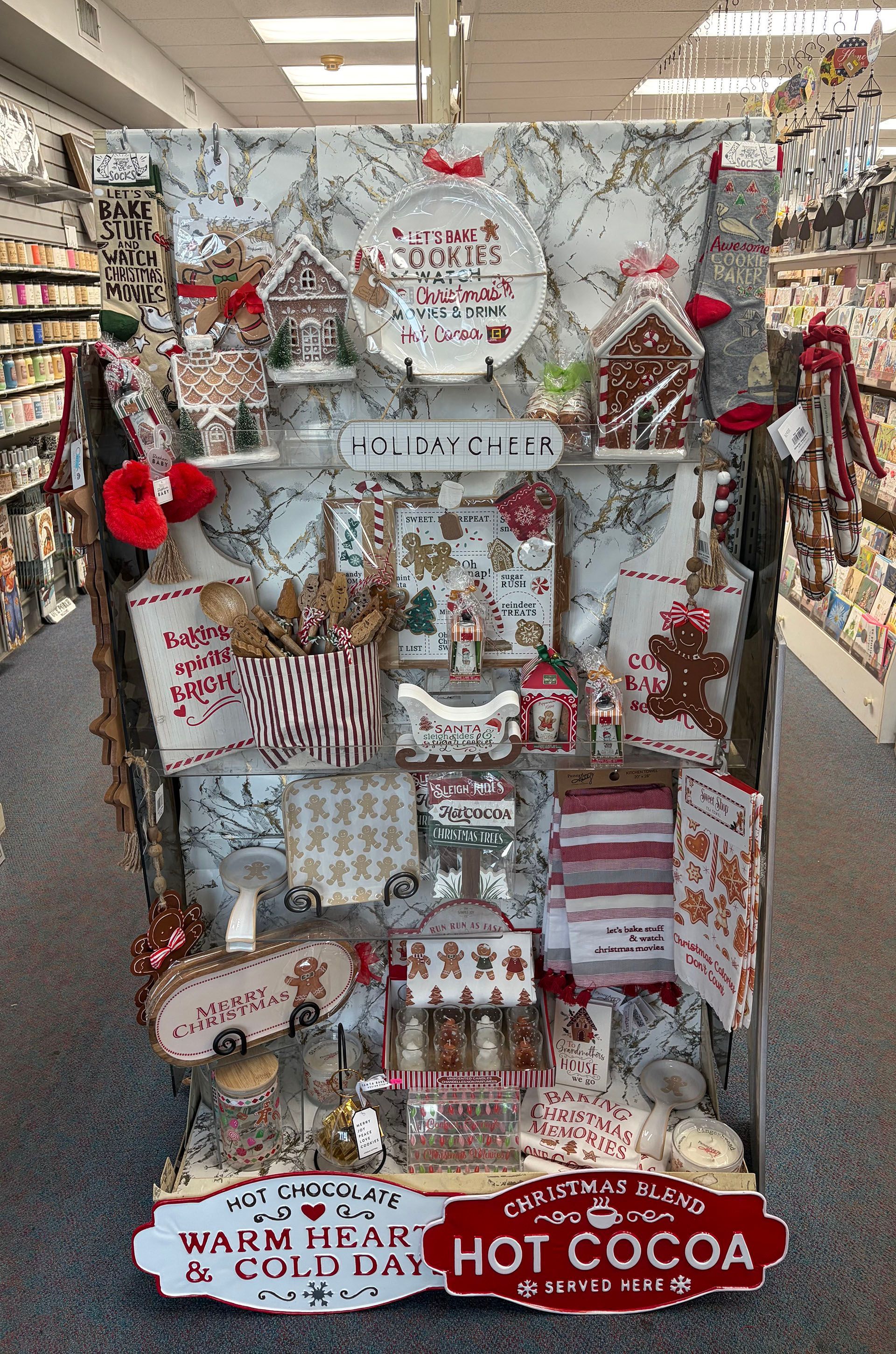 Christmas-themed store display with gingerbread houses, plates, and mugs for sale, in a retail setting.