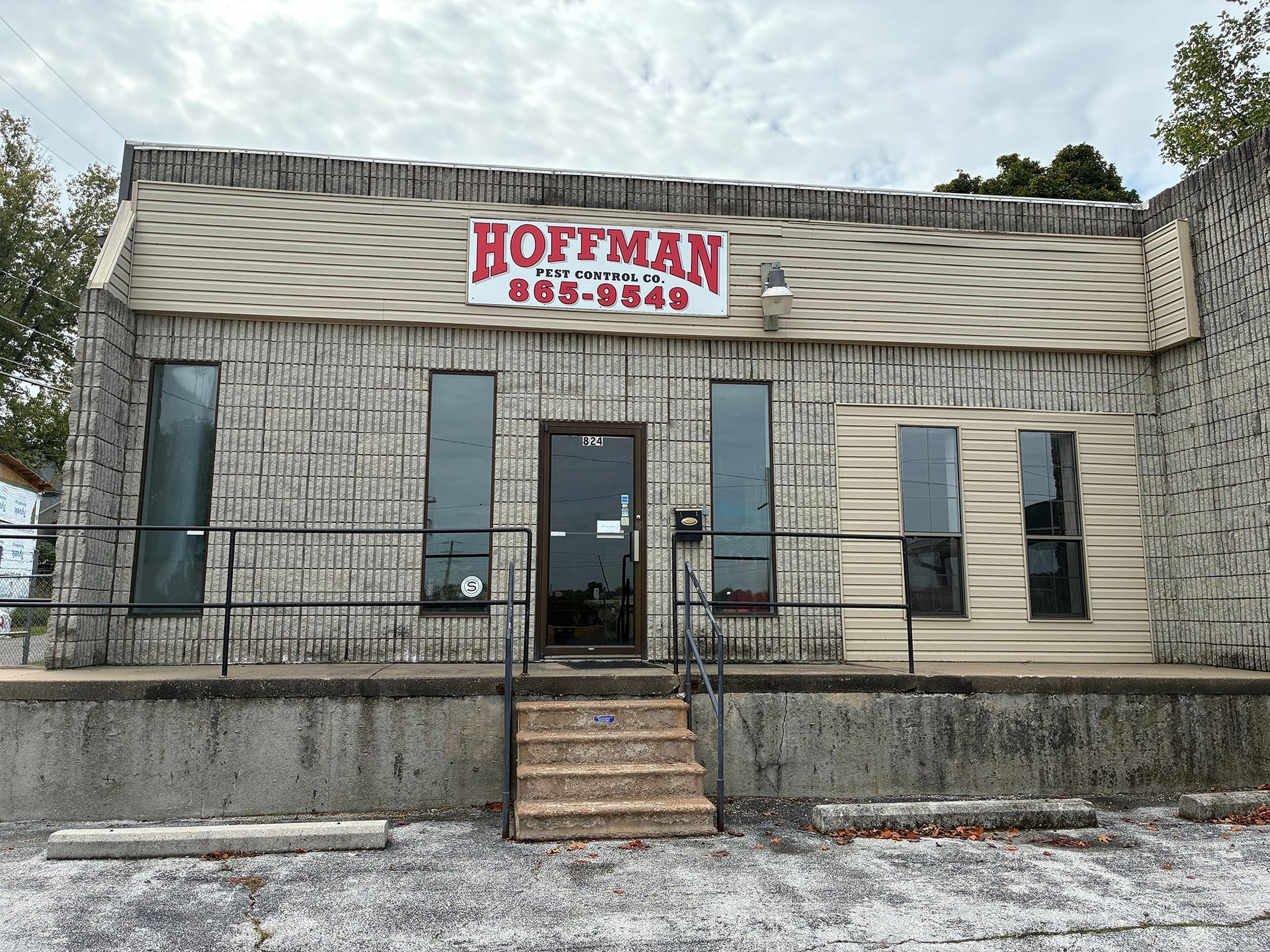 A single-story commercial building with light-colored textured stone walls and a sign for 