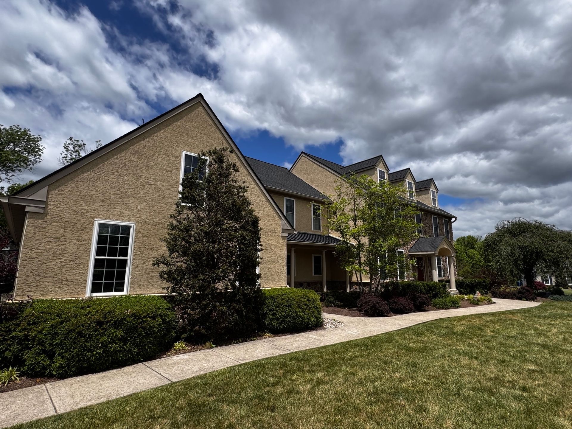 Brick apartment buildings with landscaped lawn and sidewalk under a cloudy sky