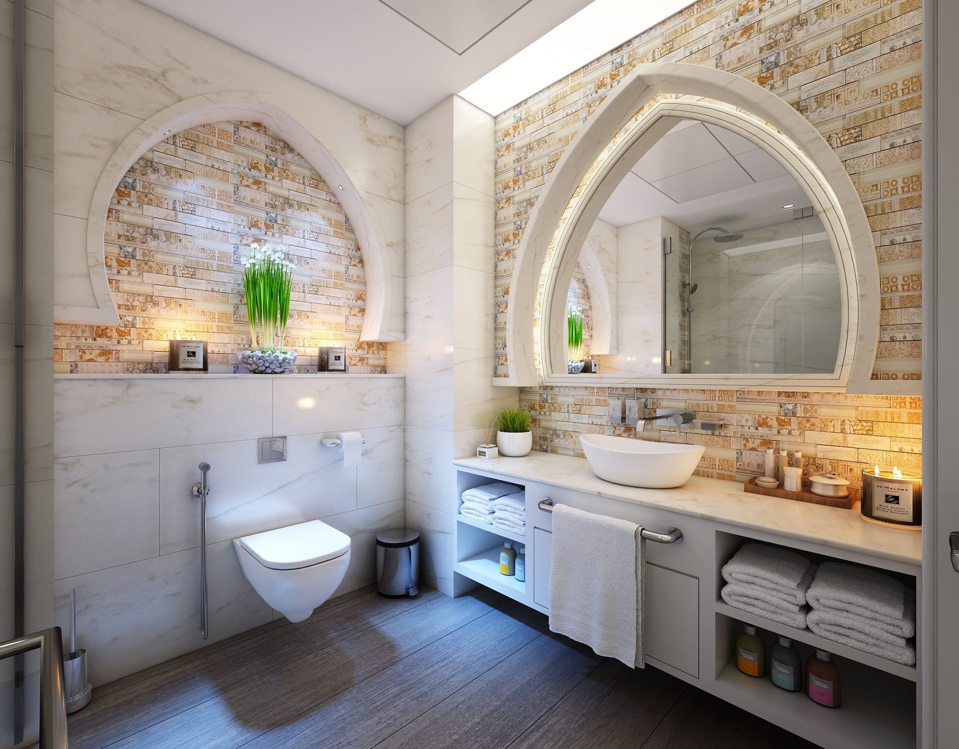 A modern bathroom with an arched wall niche, vanity with white sink, wall-mounted toilet, and cream-colored tile accents.