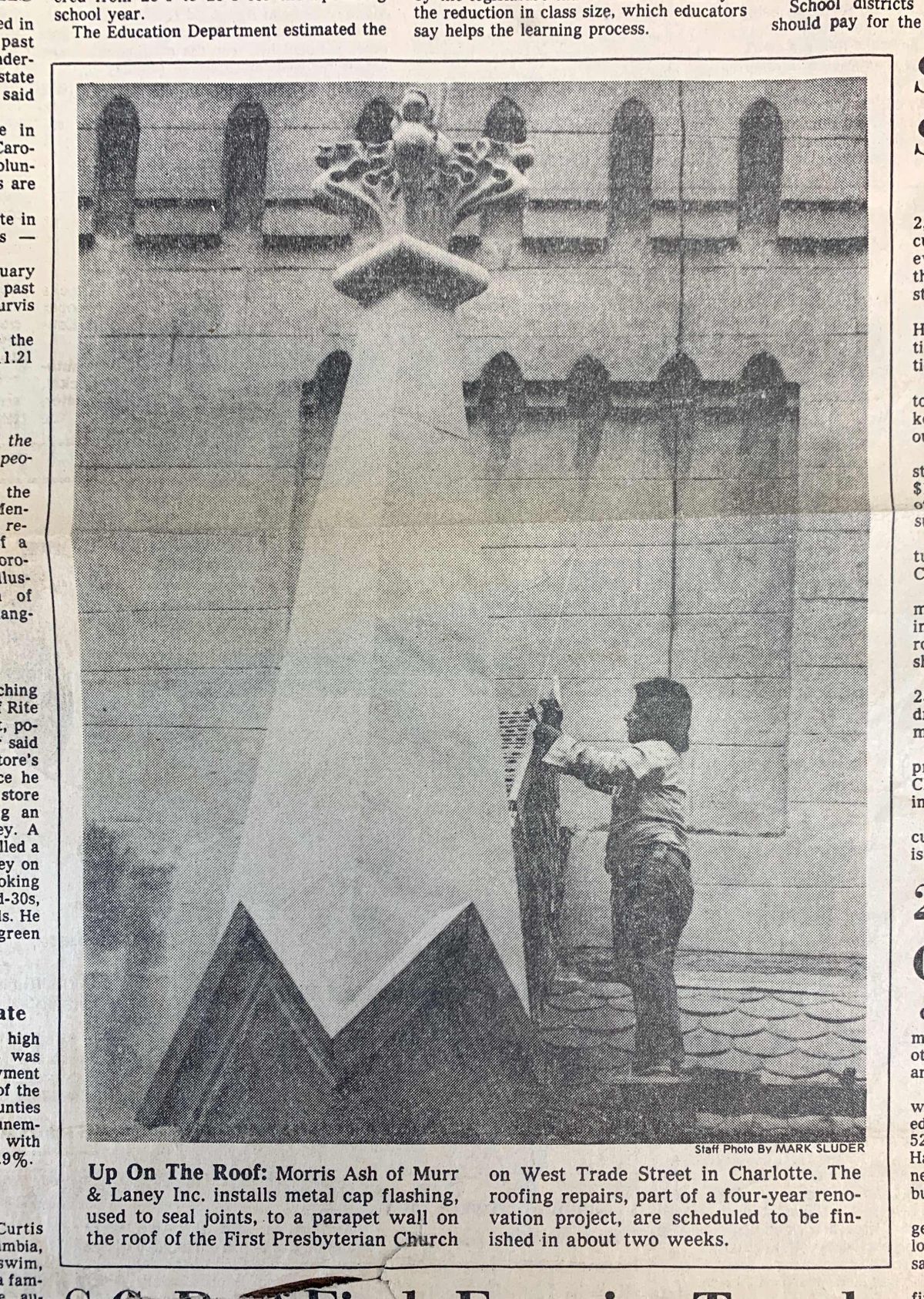 A person stands beneath a spotlight, aiming it at a building with ornate stonework. Text at the bottom reads: 