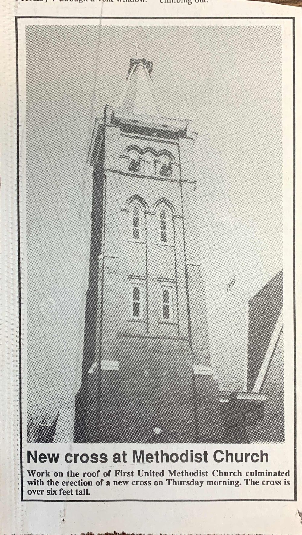 Tall brick church tower with a new cross on top.  The text 