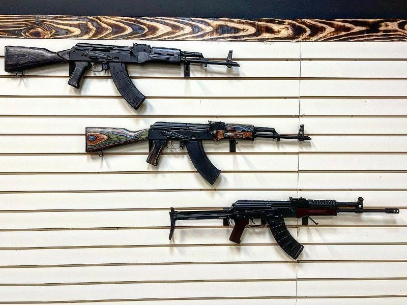 Three assault rifles are hanging on a wall.