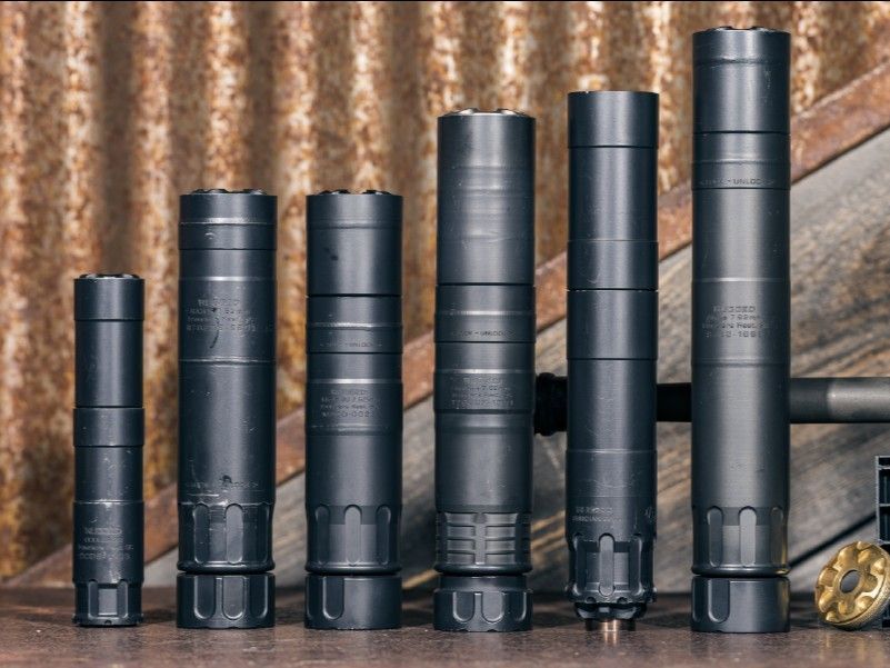 A row of silencers of different sizes are lined up on a table