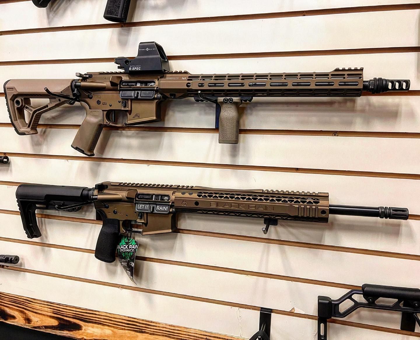 Two assault rifles are hanging on a wall in a store.